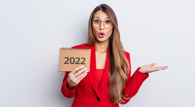 Jolie femme asiatique semblant surprise et choquée, avec la mâchoire tombée tenant un objet. notion de calendrier