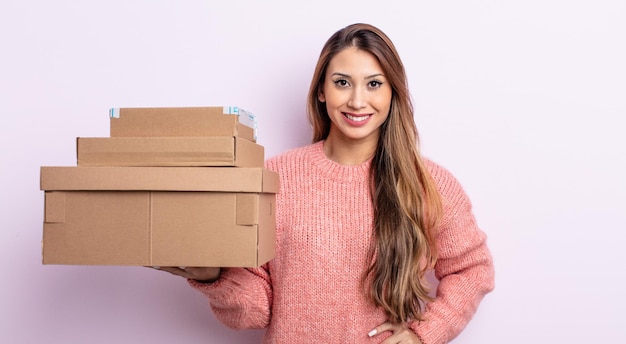 Jolie femme asiatique souriant joyeusement avec une main sur la hanche et confiante. concept de boîtes de rangement