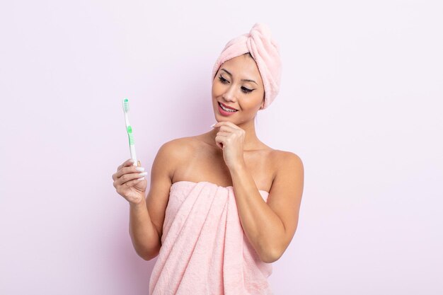 Jolie femme asiatique souriante avec une expression heureuse et confiante avec la main sur le concept de brosse à dents au menton