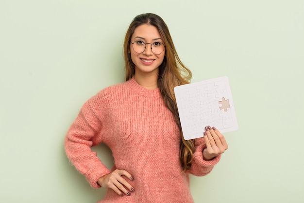 jolie femme asiatique souriante joyeusement avec une main sur la hanche et confiante. notion de casse-tête