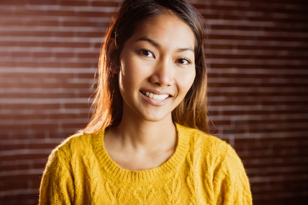 Jolie femme asiatique souriante sur le mur de briques