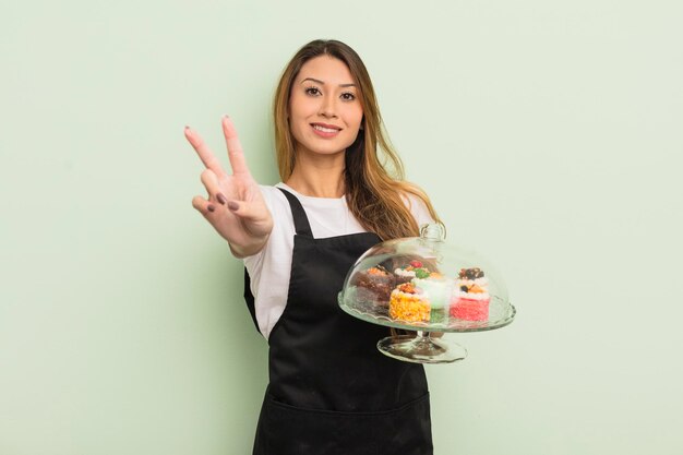 jolie femme asiatique souriante et sympathique, montrant le numéro deux. concept de gâteaux faits maison