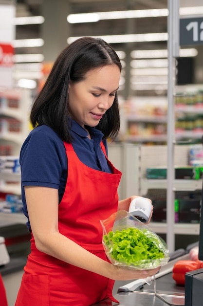 Jolie femme asiatique travaillant dans un supermarché debout à la caisse avec les bras croisés souriant