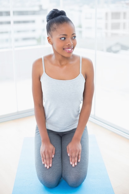 Jolie femme assise sur un tapis d&#39;exercice