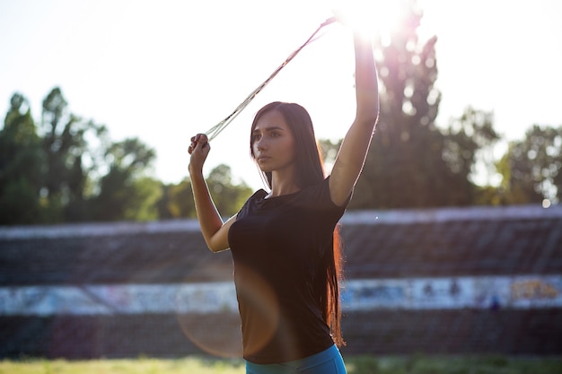 Jolie femme athlétique qui s'étend avec une corde à sauter au stade