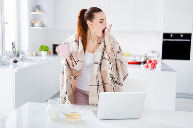 jolie femme au foyer dame couverture couverte matin prendre le petit déjeuner bâillement