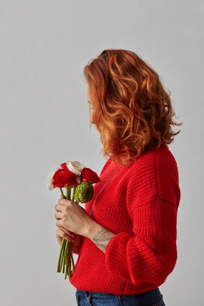 Jolie femme aux beaux cheveux roux tient un bouquet de fleurs. Vacances de printemps et d'été. Beauté, concept de mode.