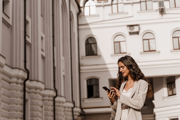 Jolie femme aux cheveux bouclés tient le téléphone dans les mains