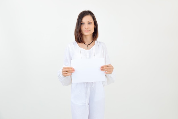 Jolie femme aux cheveux bruns souriante et confiante en studio blanc montre un modèle vierge vide promo b