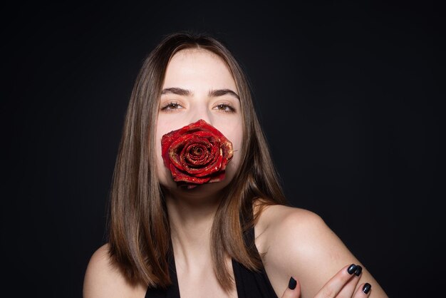 Jolie femme aux lèvres rouges et maquillage de mode avec des roses posant en studio beauté et mode portrait