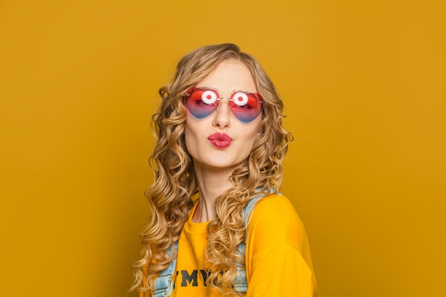 Une jolie femme aux longs cheveux bouclés souriant sur un fond jaune