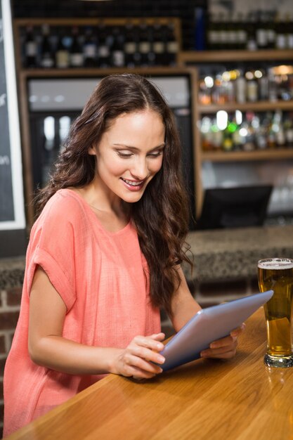 Jolie femme ayant une bière et regardant une tablette