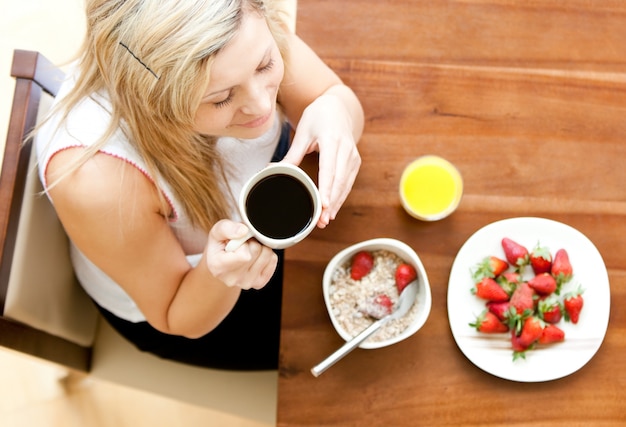 Jolie femme ayant un petit déjeuner sain dans un salon