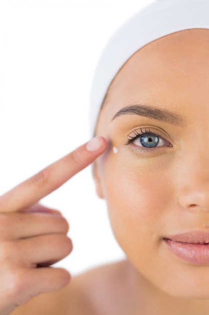 Photo jolie femme avec bandeau en mettant de la crème sur son visage