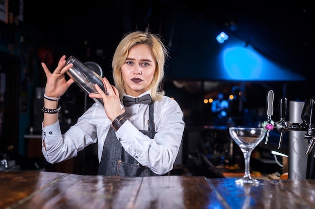 Jolie femme barman démontre ses compétences sur le comptoir tout en se tenant près du comptoir du bar dans un pub