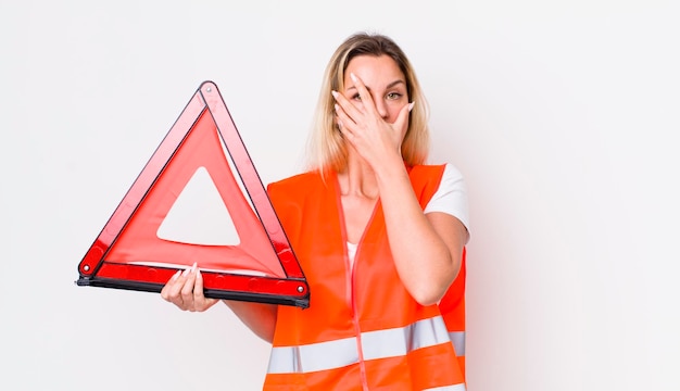 Photo jolie femme blonde à l'air choquée, effrayée ou terrifiée, couvrant le visage avec le concept d'accident de triangle de voiture à la main