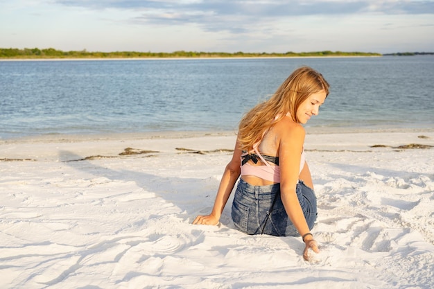 Jolie femme blonde appréciant de toucher le sable
