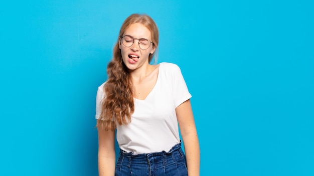 Jolie femme blonde avec une attitude gaie, insouciante et rebelle, plaisantant et tirant la langue, s'amusant