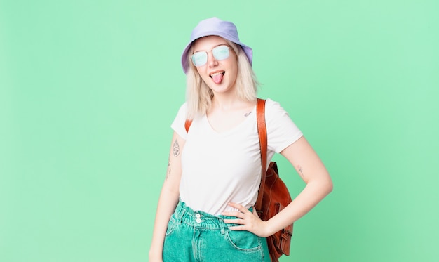 Jolie femme blonde avec une attitude joyeuse et rebelle, plaisantant et tirant la langue. concept d'été