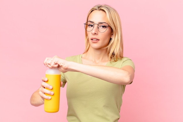 Jolie femme blonde ayant un smoothie orange