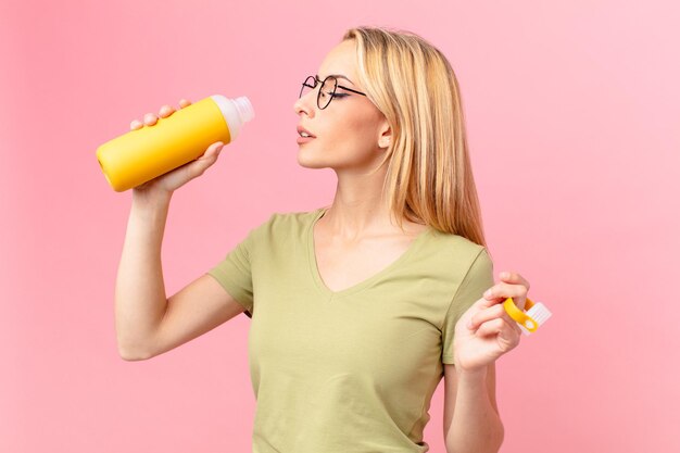 Jolie femme blonde ayant un smoothie orange