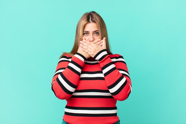 Jolie femme blonde bien roulée couvrant la bouche avec les mains avec un choqué