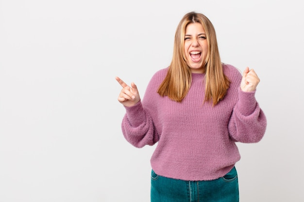 Jolie femme blonde bien roulée criant agressivement avec une expression de colère