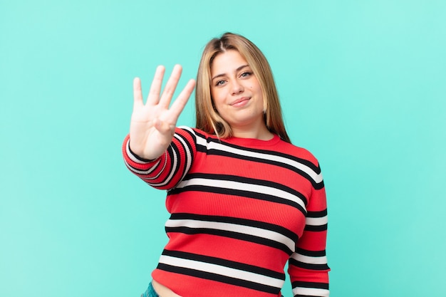 Photo jolie femme blonde bien roulée souriante et semblant amicale, montrant le numéro quatre