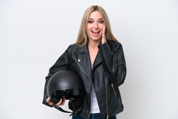 Jolie femme blonde avec un casque de moto isolé sur fond blanc avec une expression faciale surprise et choquée