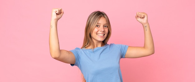 Jolie femme blonde criant triomphalement, ressemblant à un gagnant excité, heureux et surpris, célébrant