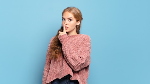 Jolie femme blonde demandant le silence et la tranquillité, faisant des gestes avec le doigt devant la bouche, disant chut ou gardant un secret