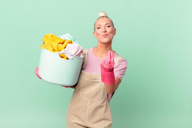 Jolie femme blonde faisant un geste de capice ou d'argent, vous disant de payer le concept de lavage de vêtements