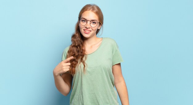 Jolie femme blonde à la fierté, confiante et heureuse, souriante et pointant vers soi ou faisant signe numéro un