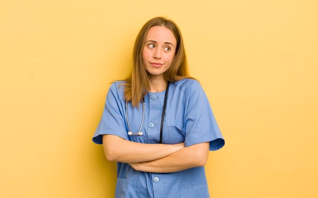 Jolie femme blonde haussant les épaules se sentant confus et incertain concept d'infirmière