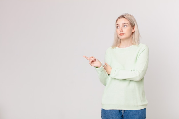 jolie femme blonde haussant les épaules, se sentant confuse et incertaine