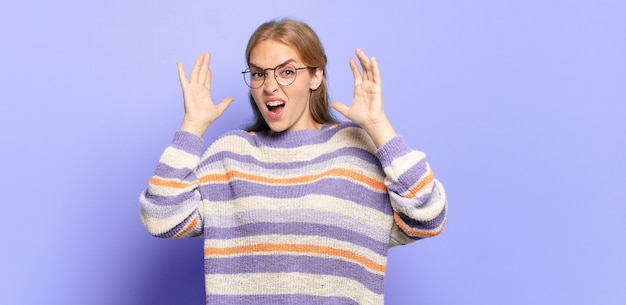 Jolie femme blonde hurlant les mains en l'air, se sentant furieuse, frustrée, stressée et bouleversée