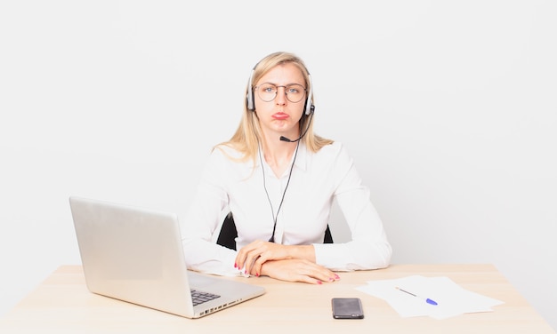 Jolie femme blonde jeune femme blonde se sentant triste et pleurnicharde avec un regard malheureux et pleurant et travaillant avec un ordinateur portable
