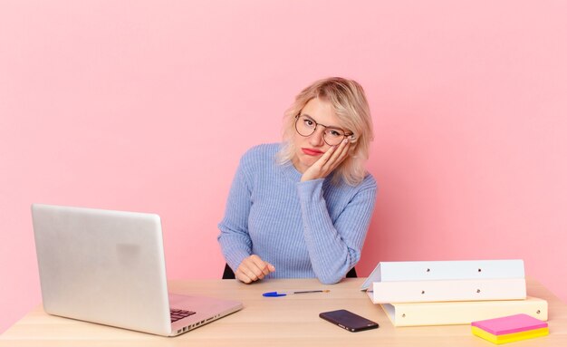 Jolie femme blonde jeune jolie femme se sentant ennuyée, frustrée et endormie après une période fastidieuse. concept de bureau d'espace de travail