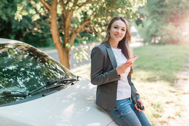 Jolie femme blonde à la mode avec un téléphone intelligent et des clés de voiture