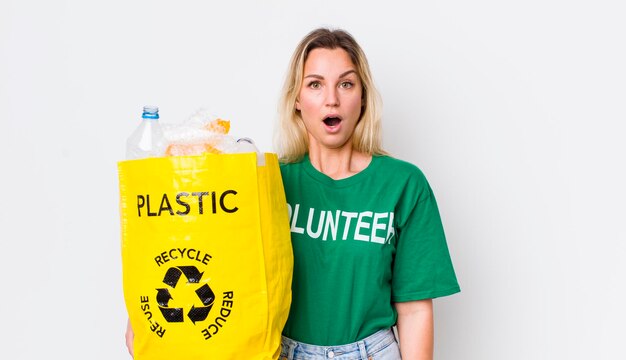 Jolie femme blonde à la recherche de concept de recyclage très choqué ou surpris