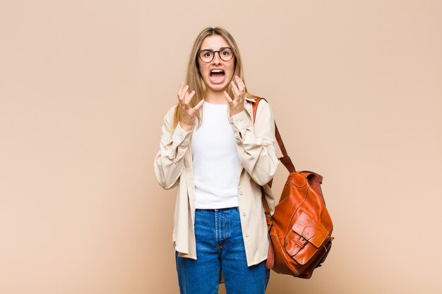 Jolie femme blonde à la recherche désespérée et frustrée, stressée, malheureuse et agacée, criant et hurlant