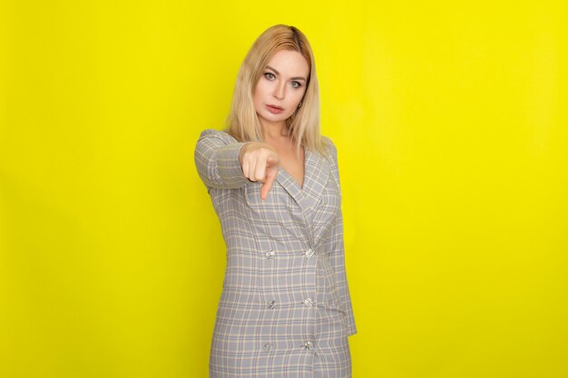 Jolie femme blonde en robe veste à carreaux sur jaune