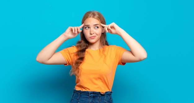 Jolie femme blonde se sentant confuse ou doutant, se concentrant sur une idée, réfléchissant, cherchant à copier l'espace sur le côté