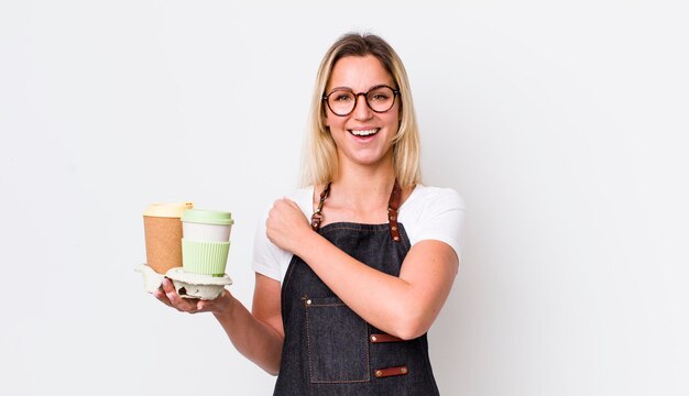 Jolie femme blonde se sentant heureuse et faisant face à un défi ou célébrant le concept de café à emporter