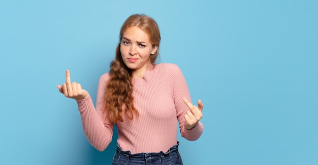 Jolie femme blonde se sentant provocante, agressive et obscène, retournant le majeur, avec une attitude rebelle