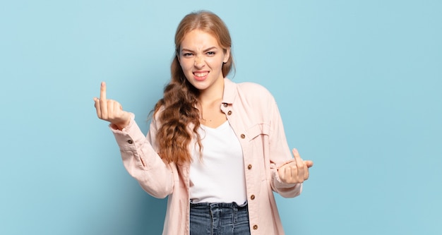 Jolie femme blonde se sentant provocante, agressive et obscène, retournant le majeur, avec une attitude rebelle