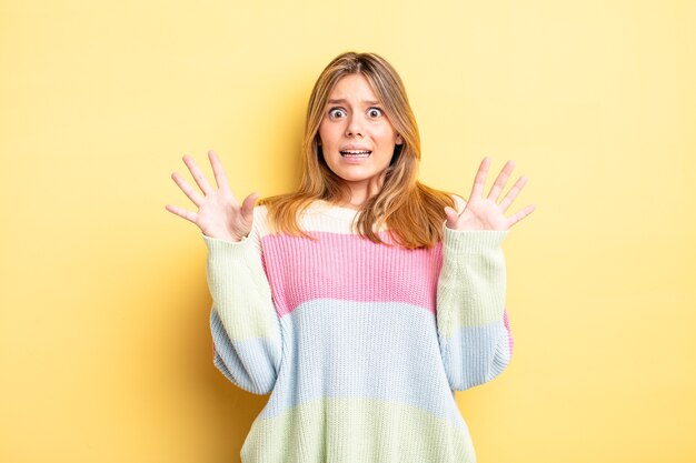 Jolie femme blonde se sentant stupéfaite et effrayée, craignant quelque chose d'effrayant, les mains ouvertes devant lui disant de rester à l'écart