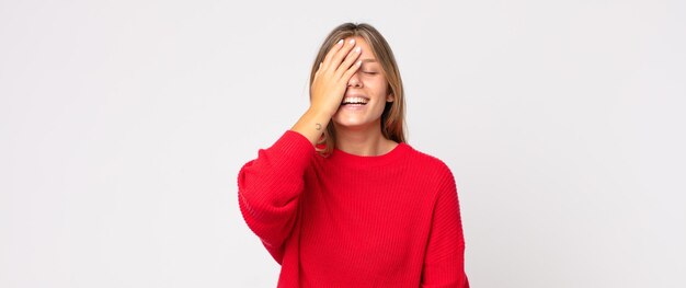 Jolie femme blonde semblant choquée et étonnée, avec la mâchoire baissée de surprise en réalisant quelque chose d'incroyable