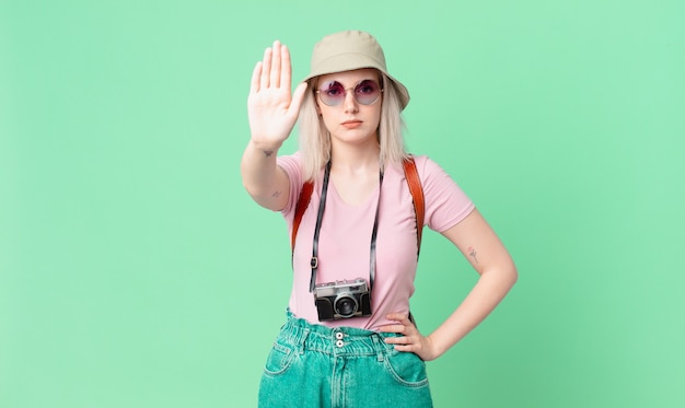 Jolie femme blonde à la sérieuse montrant la paume ouverte faisant un geste d'arrêt. concept d'été