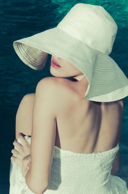 jolie femme blonde avec son chapeau au bord de la mer